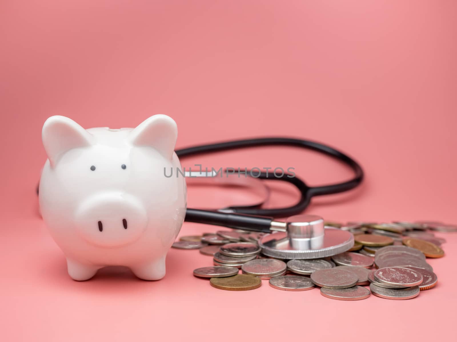 Stethoscope on the pile of money and piggy bank on pink background.
Financial health check concept, debt and finance crisis.