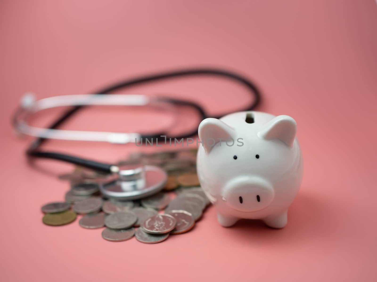 Stethoscope on the pile of money and piggy bank on pink background.
Financial health check concept, debt and finance crisis.