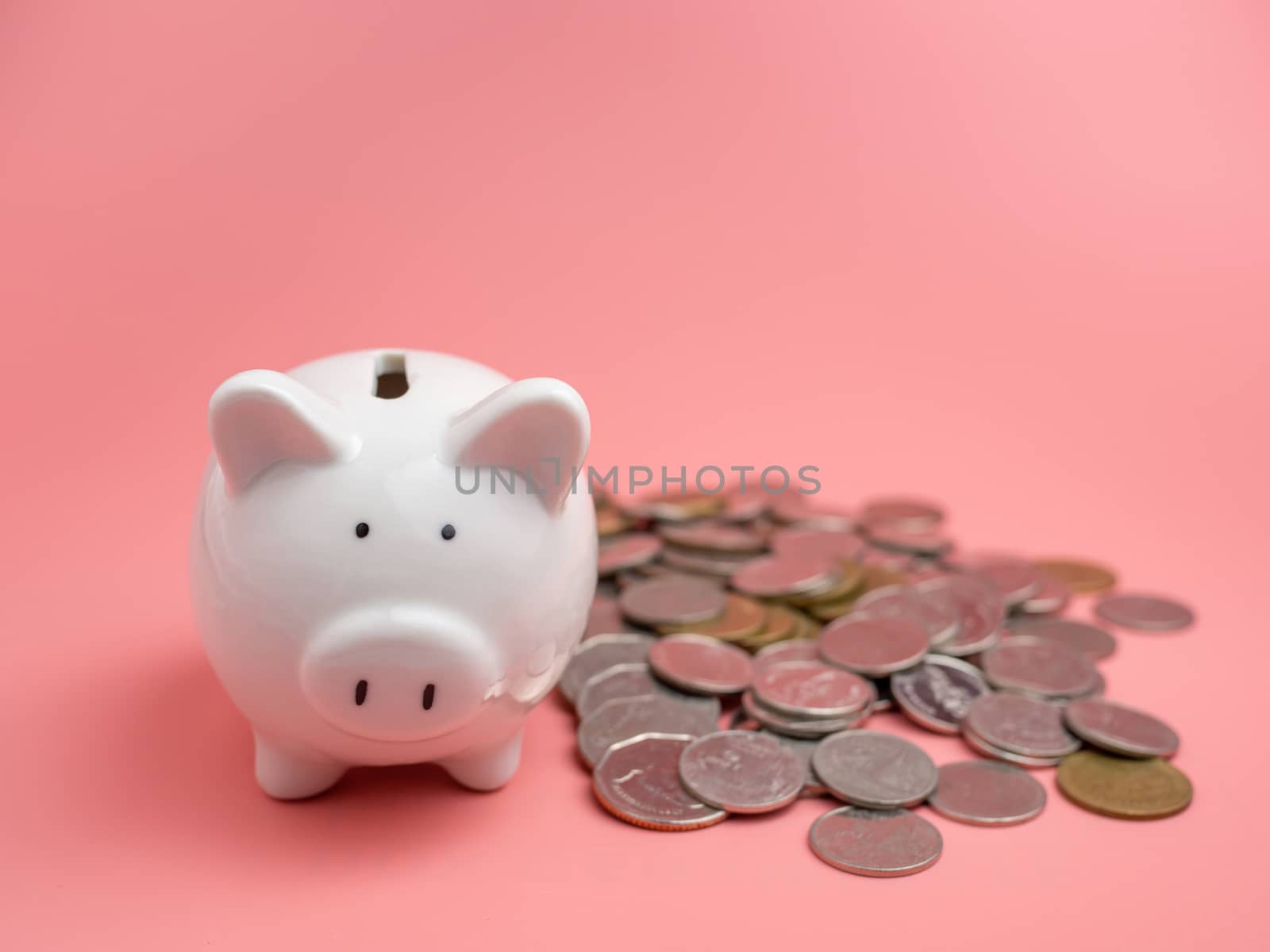 White piggy bank With a pile of coins On a pink background. saving money concept.