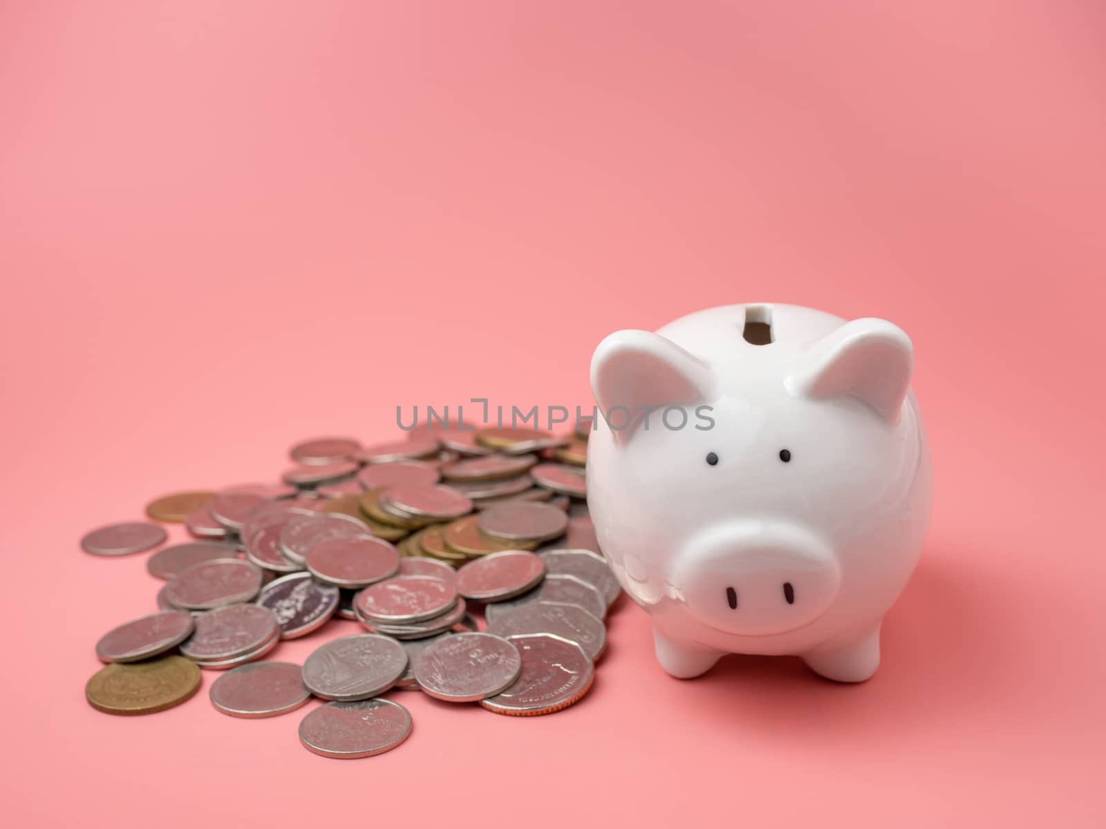 White piggy bank With a pile of coins On a pink background. saving money concept.