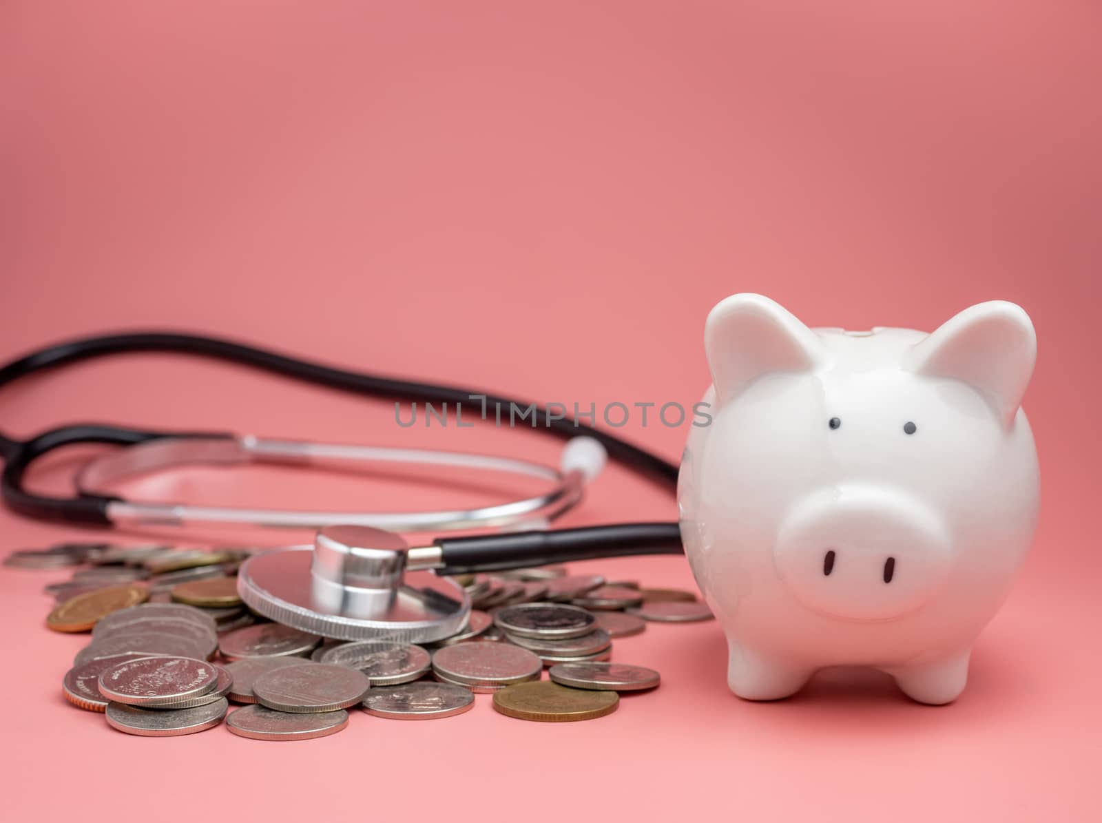 Stethoscope on the pile of money and piggy bank on pink backgrou by Unimages2527