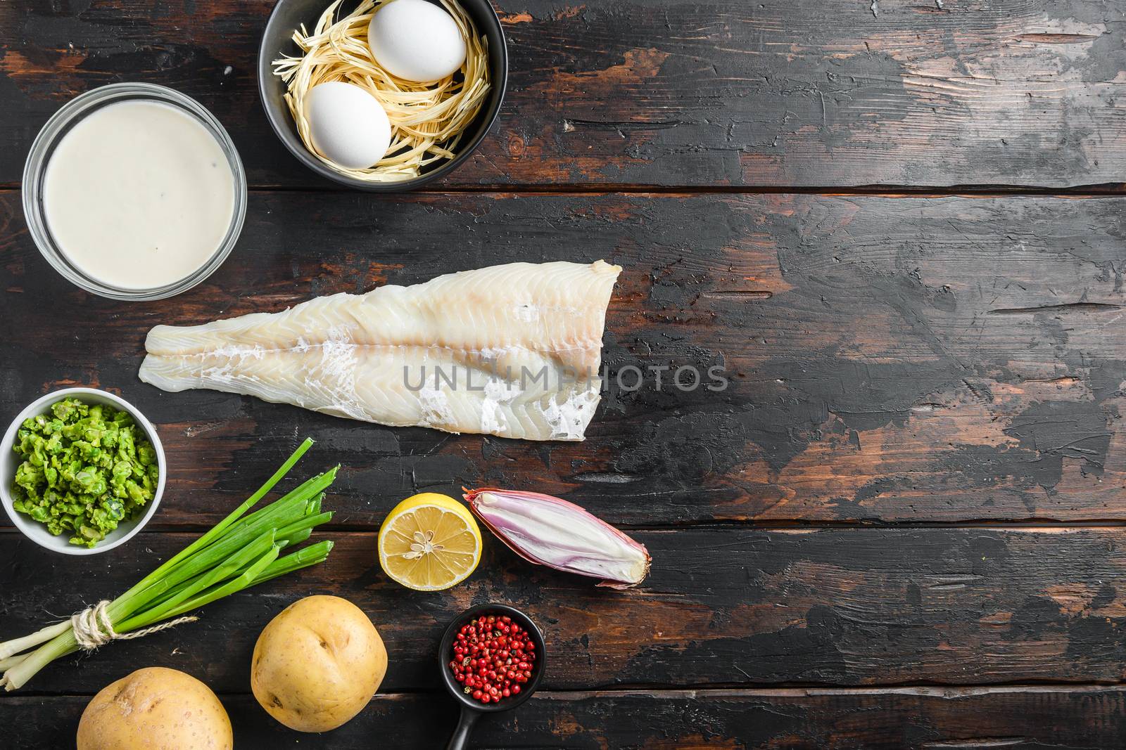 Organic fish and chips ingredients white fish fillet beer batter, potatoe, tartar sauce, minty mushy peas, lemon , shallot, mint, garlic, salt, peppercorns on rustic old wood table top view horisontal space for text.