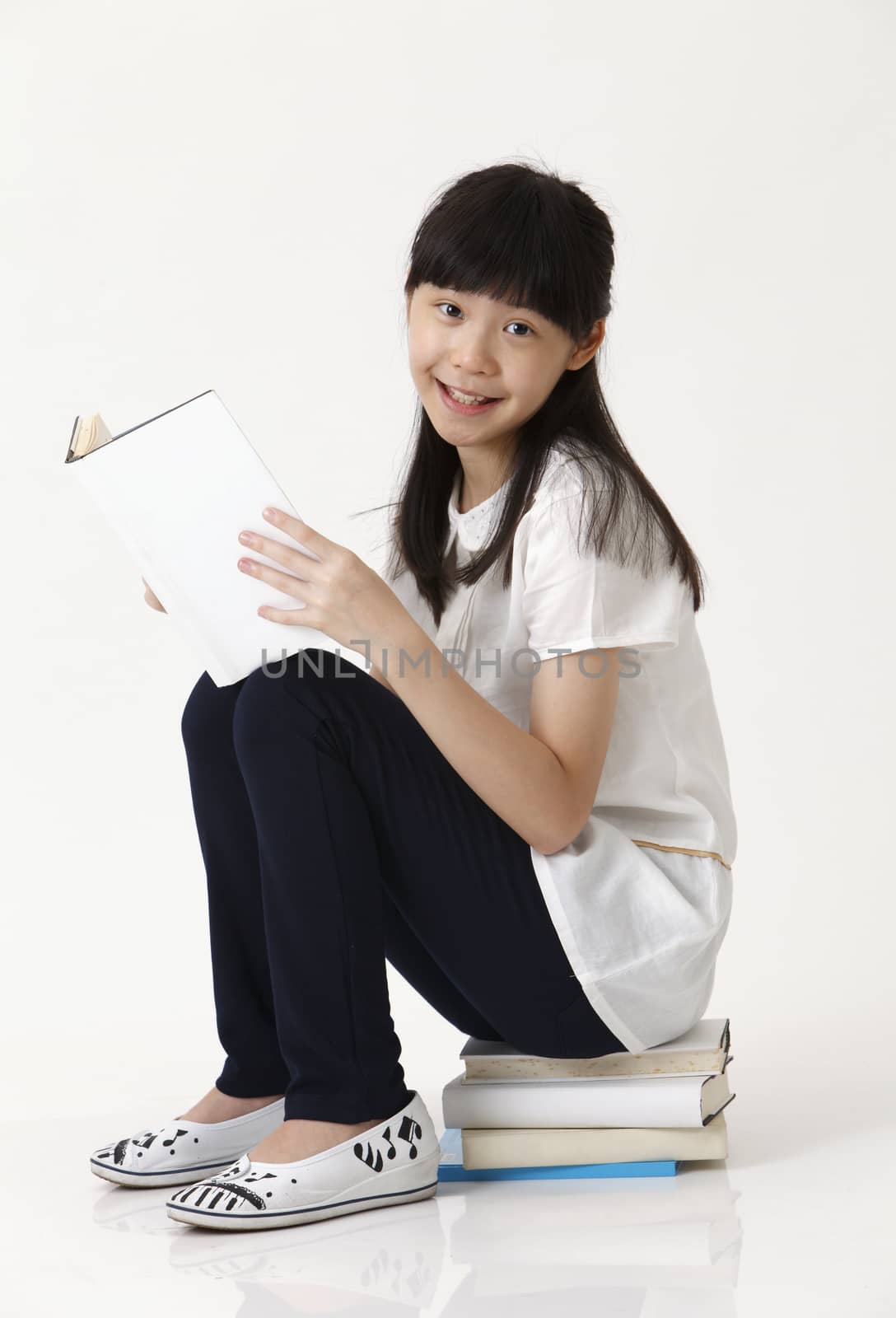 chinese girl sat on books looking at camera
