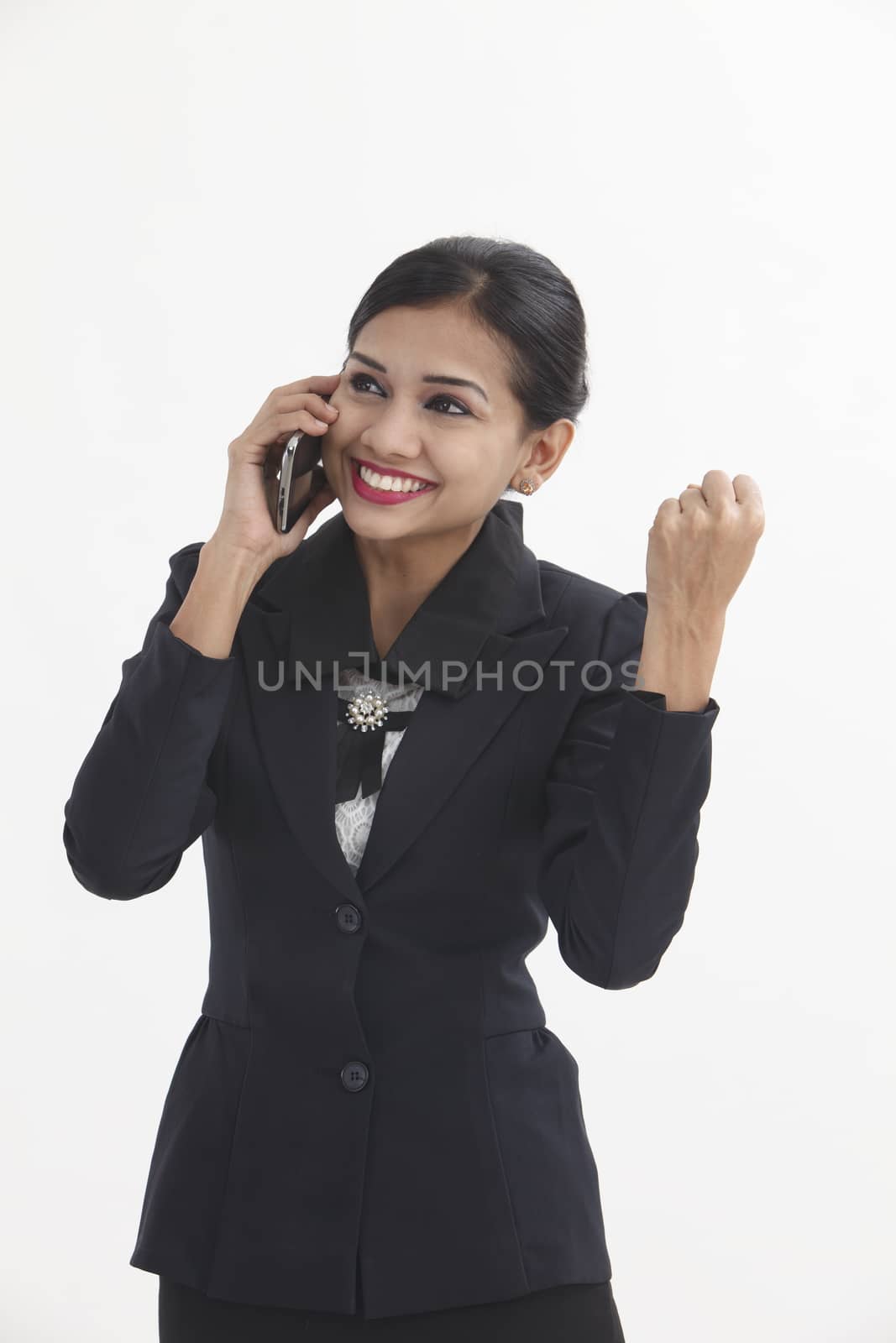 Happy business female with cell phone with arm raised in excitement isolated on white background