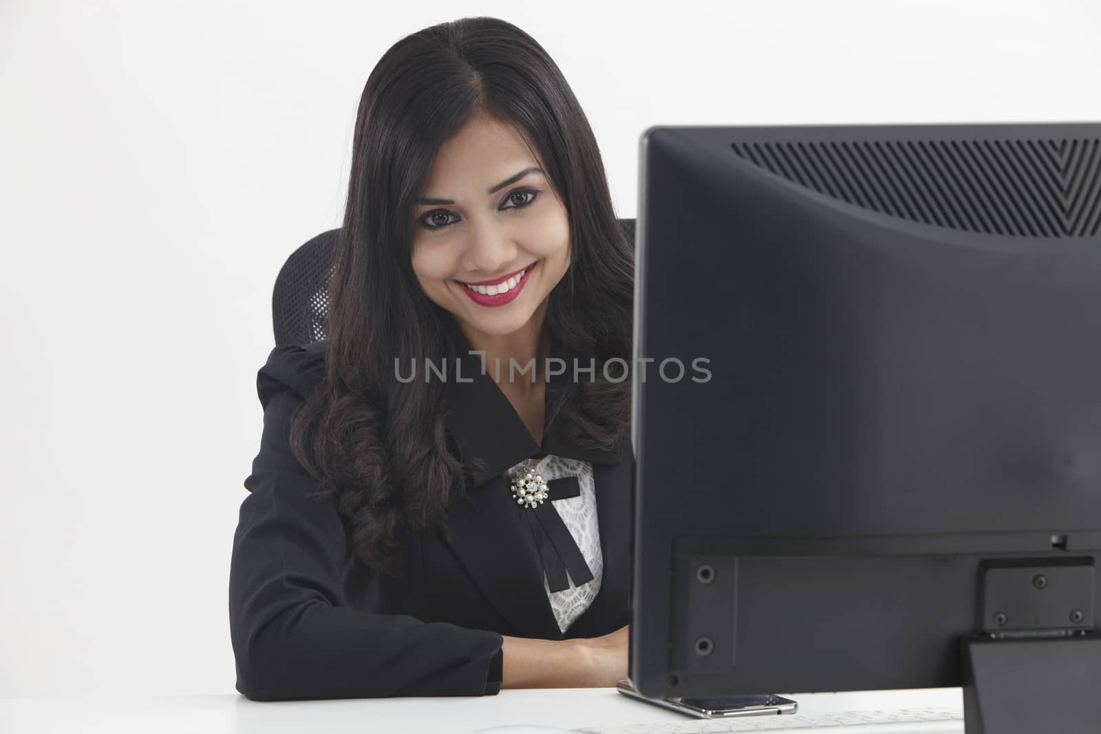 business woman sitting in front monitor looking at camera