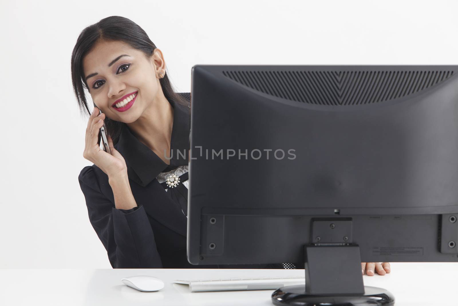 woman sitting in front of the monitor talking on the phone
