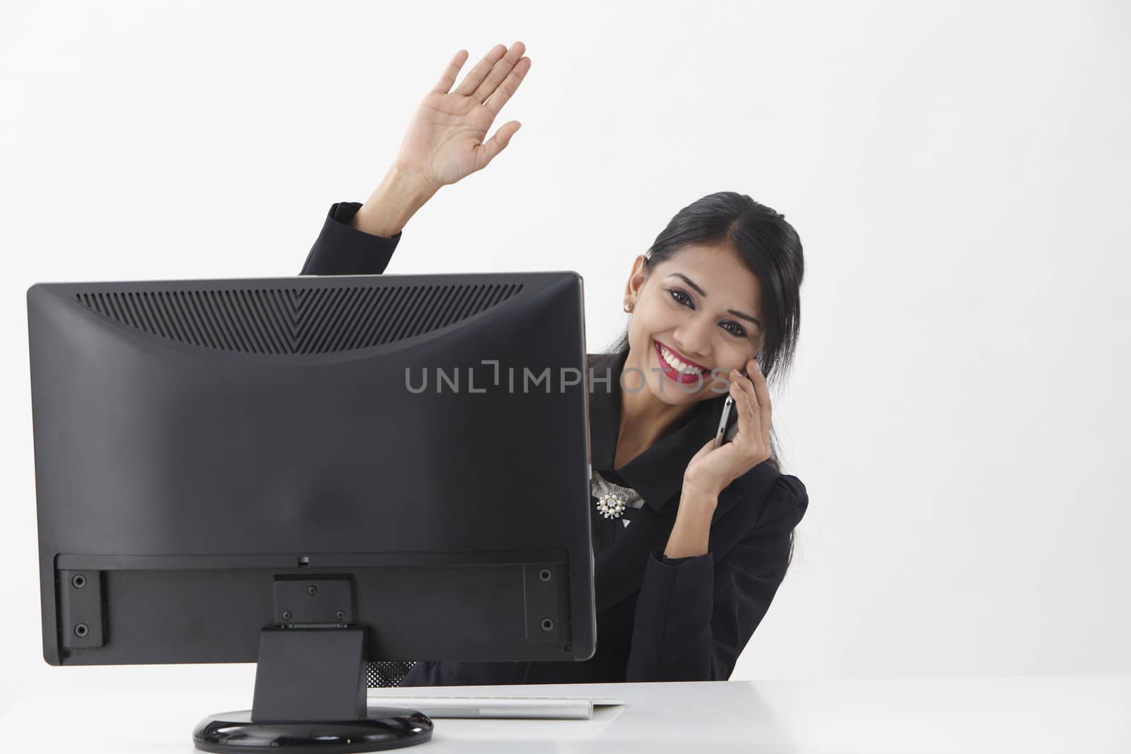 business woman sitting in front of computer,talking and waving to camera