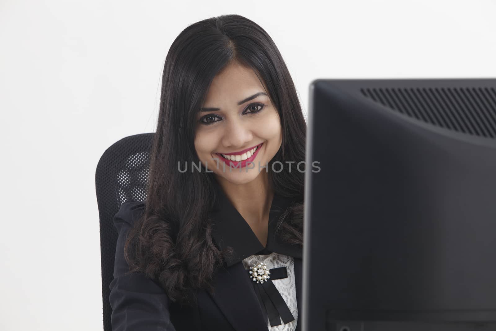 business woman sitting in front monitor looking at camera