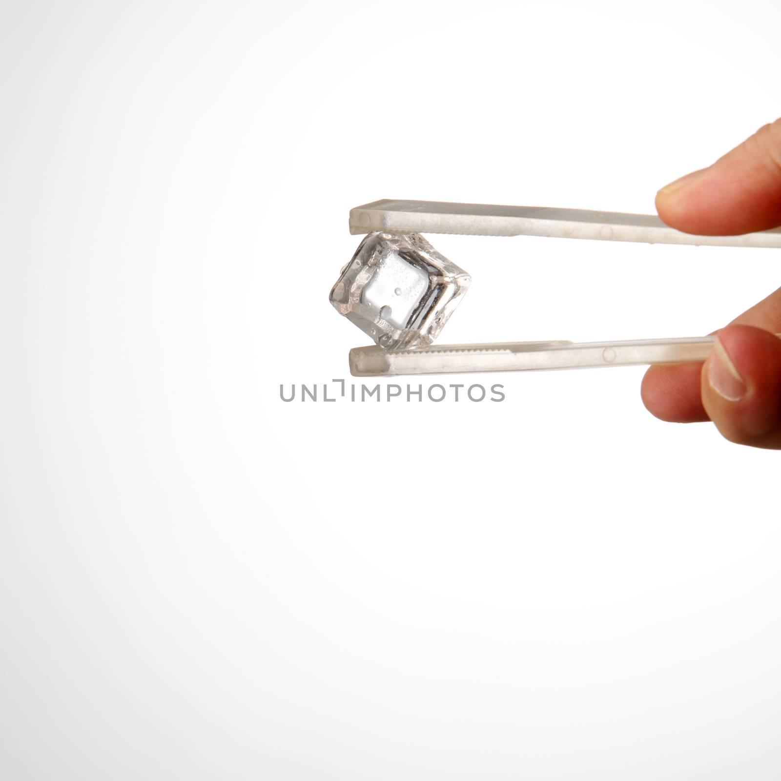 hand holding tongs with a ice cube