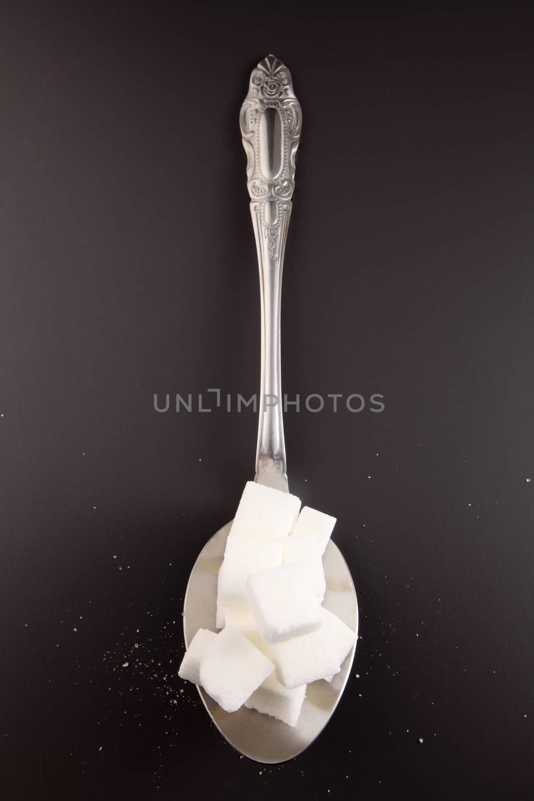 big or super size spoon with pile of cube white sugar
