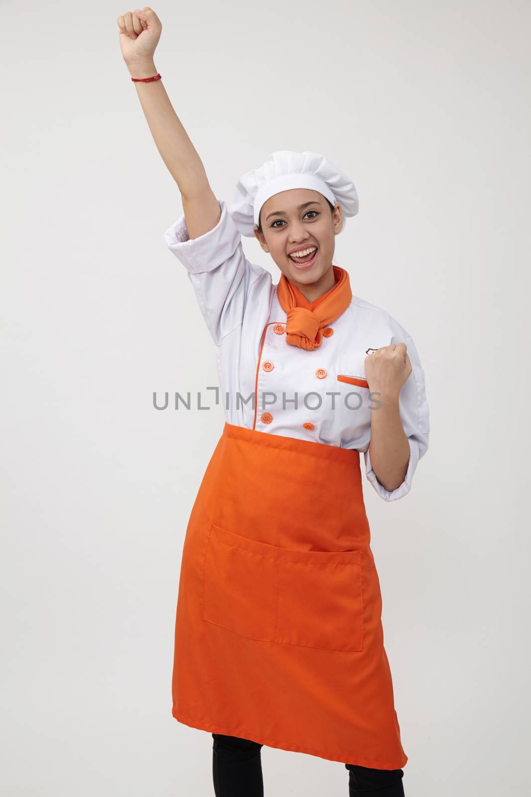 Portrait of a Indian woman with chef uniform with arm's up