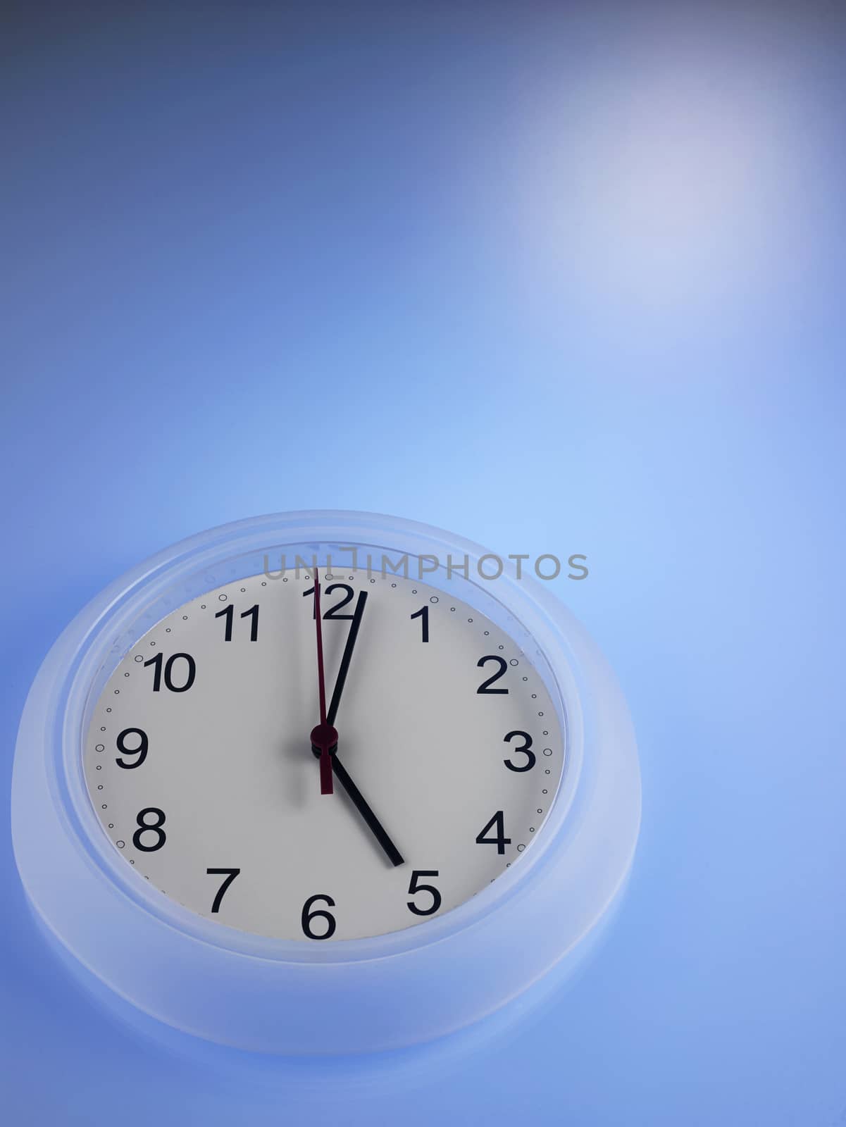 Clock showing 5 o'clock on a blue wall