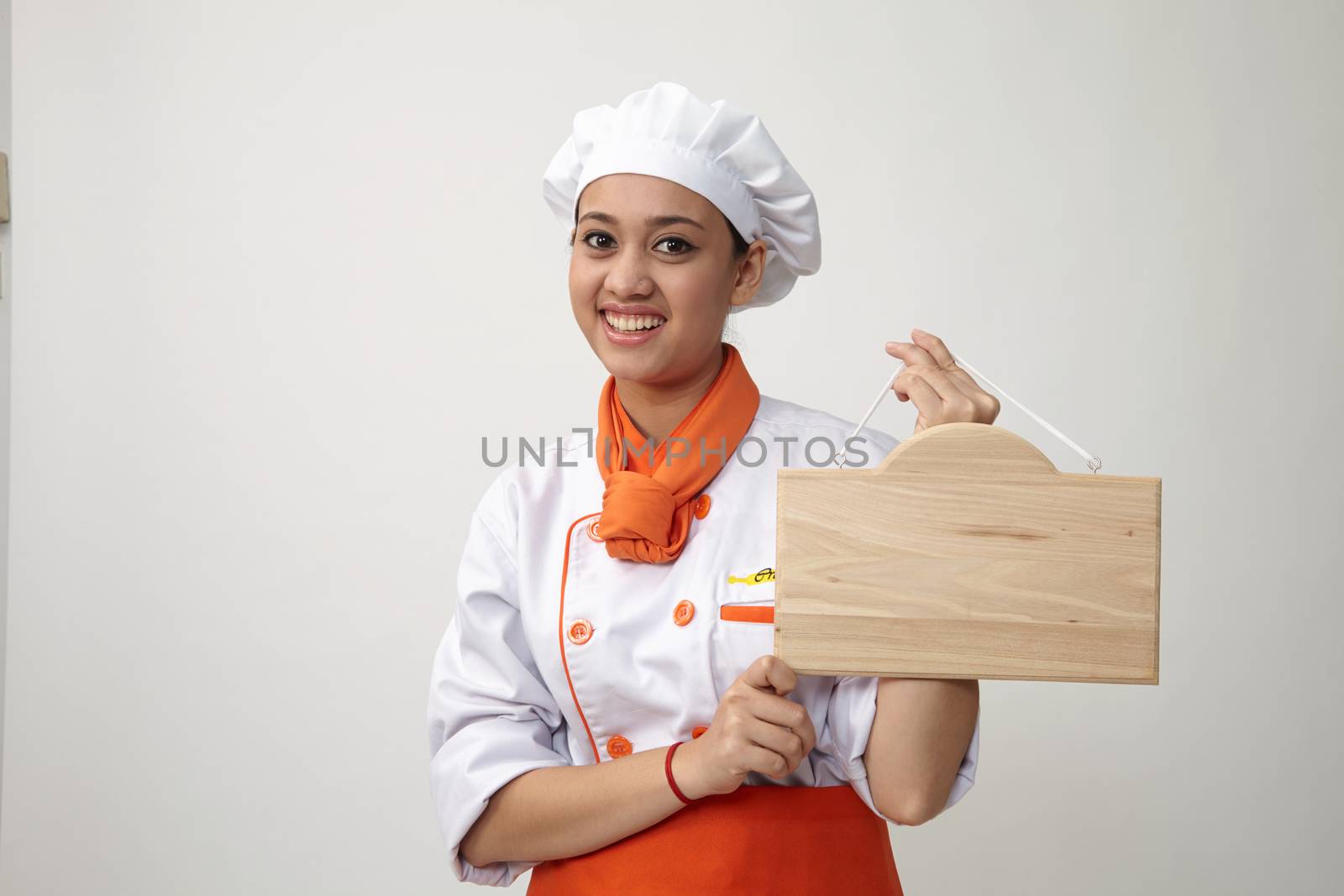  Indian woman with chef uniform holding a woden plank