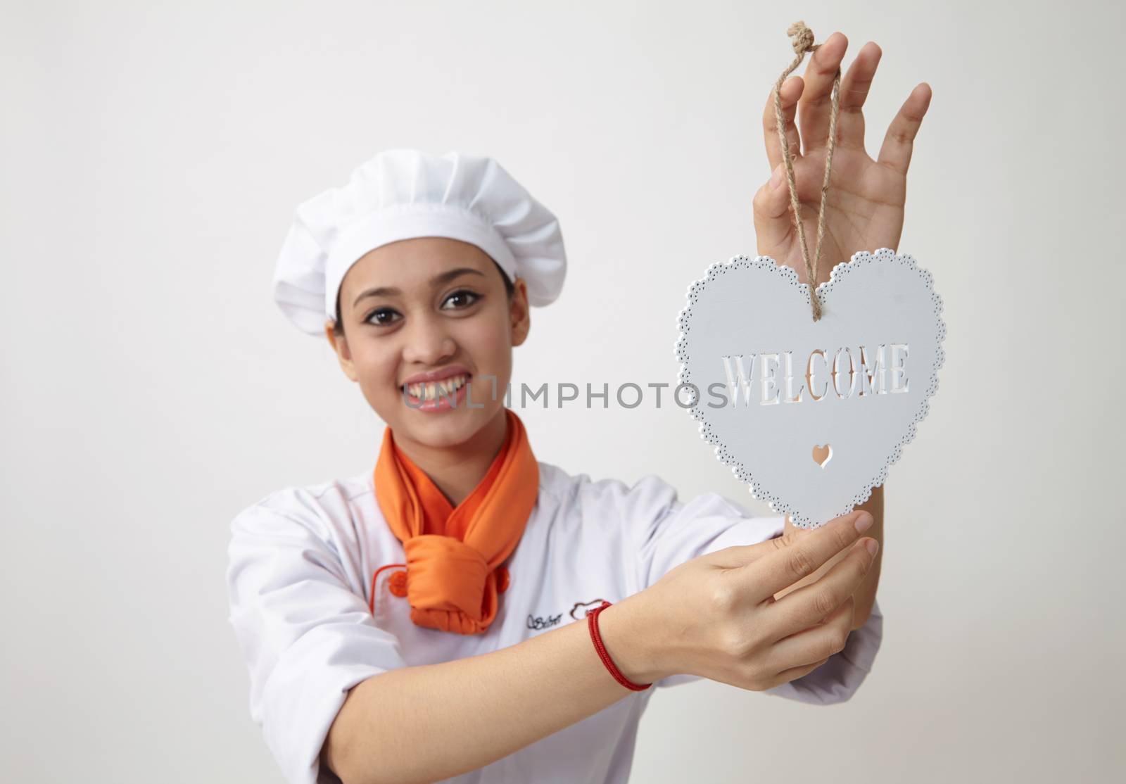 Indian woman with chef uniform holding a welcome signage