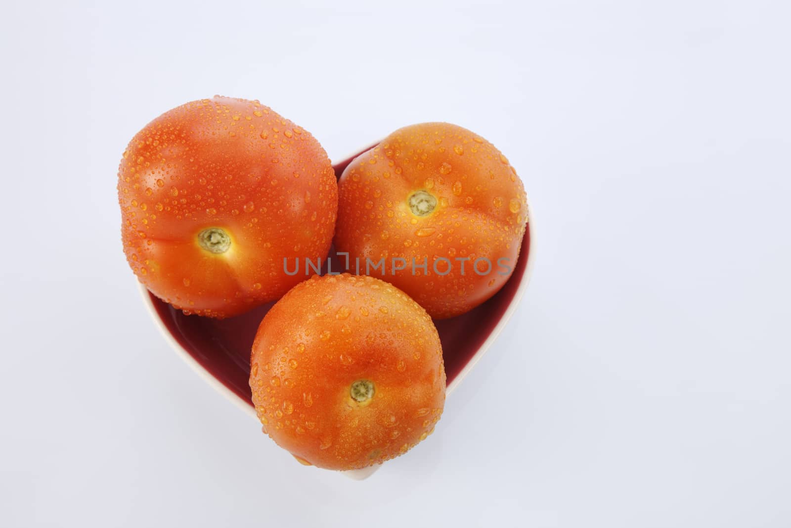 fresh red delicious tomatoes in heart-shape plate