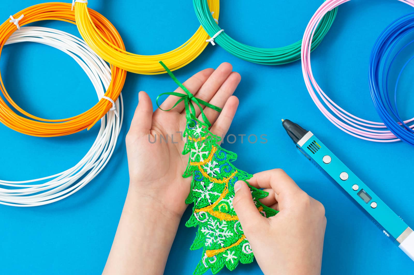 Child makes toys for Christmas tree with 3D pen. Original art project for children. New technology. DIY concept. Step by step photo instruction. Step 4. Tie ribbon