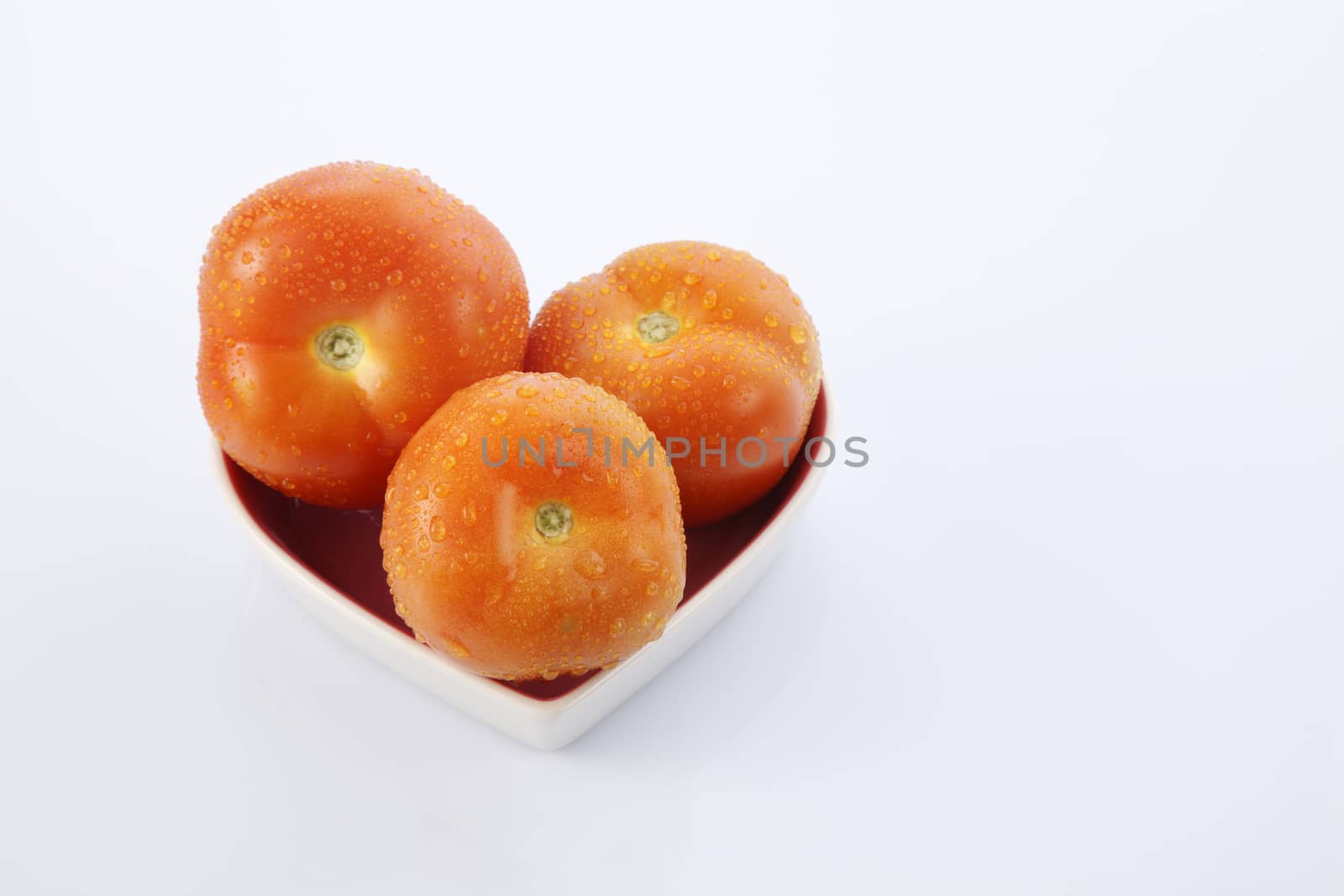 fresh red delicious tomatoes in heart-shape plate