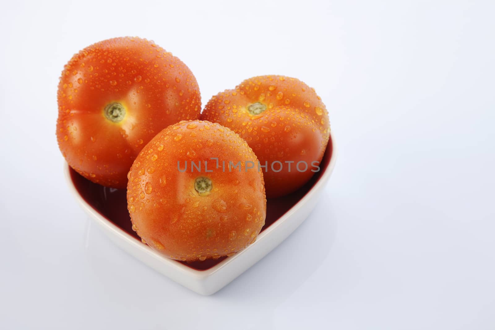 fresh red delicious tomatoes in heart-shape plate