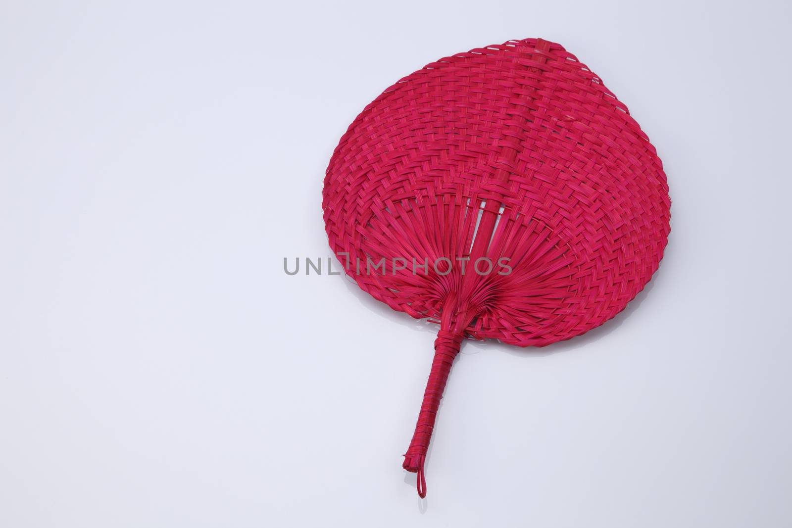 Red color native fan made from palm leaves on white background