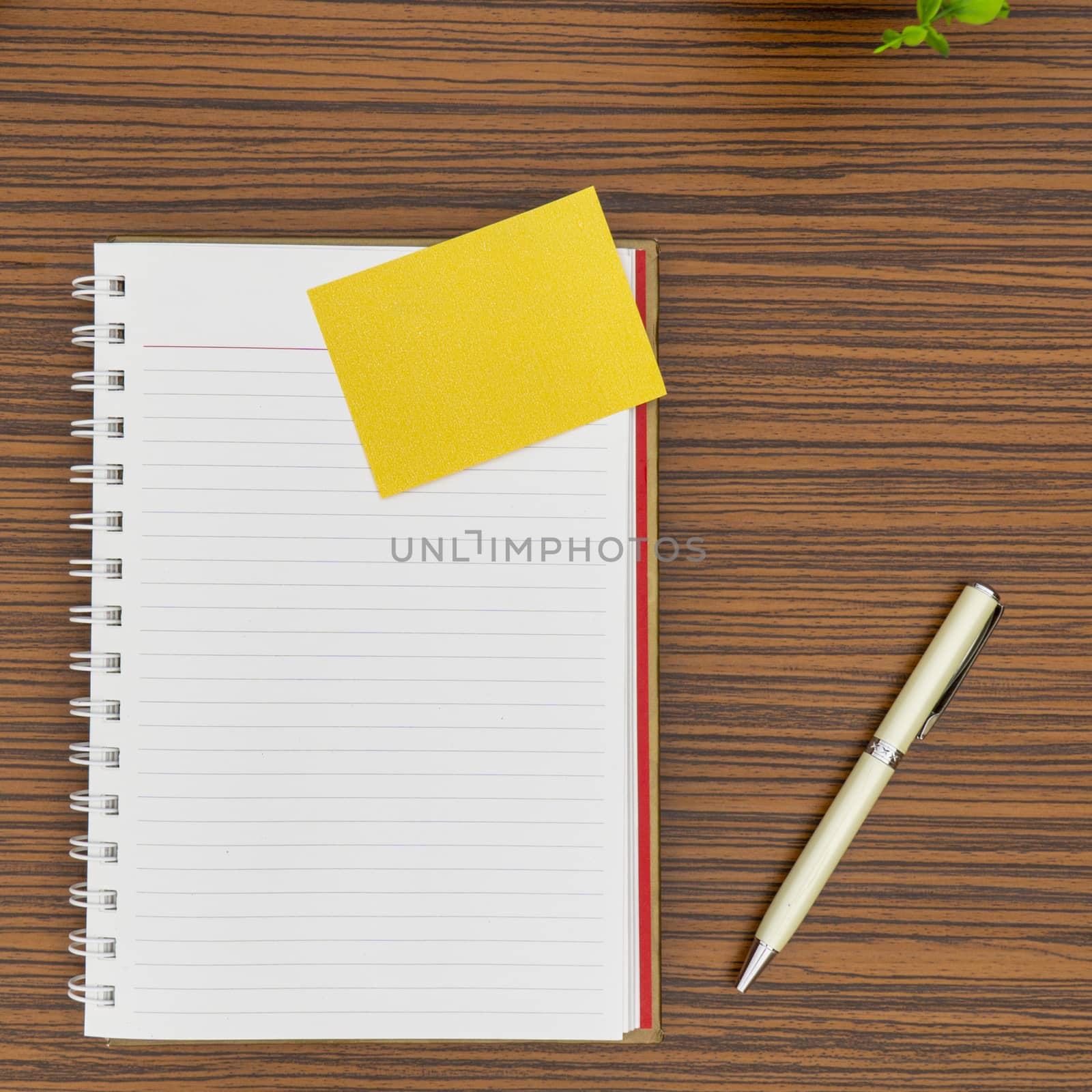 Personal notepad, yellow paper note and a pen on a zebra wood brown striped table.