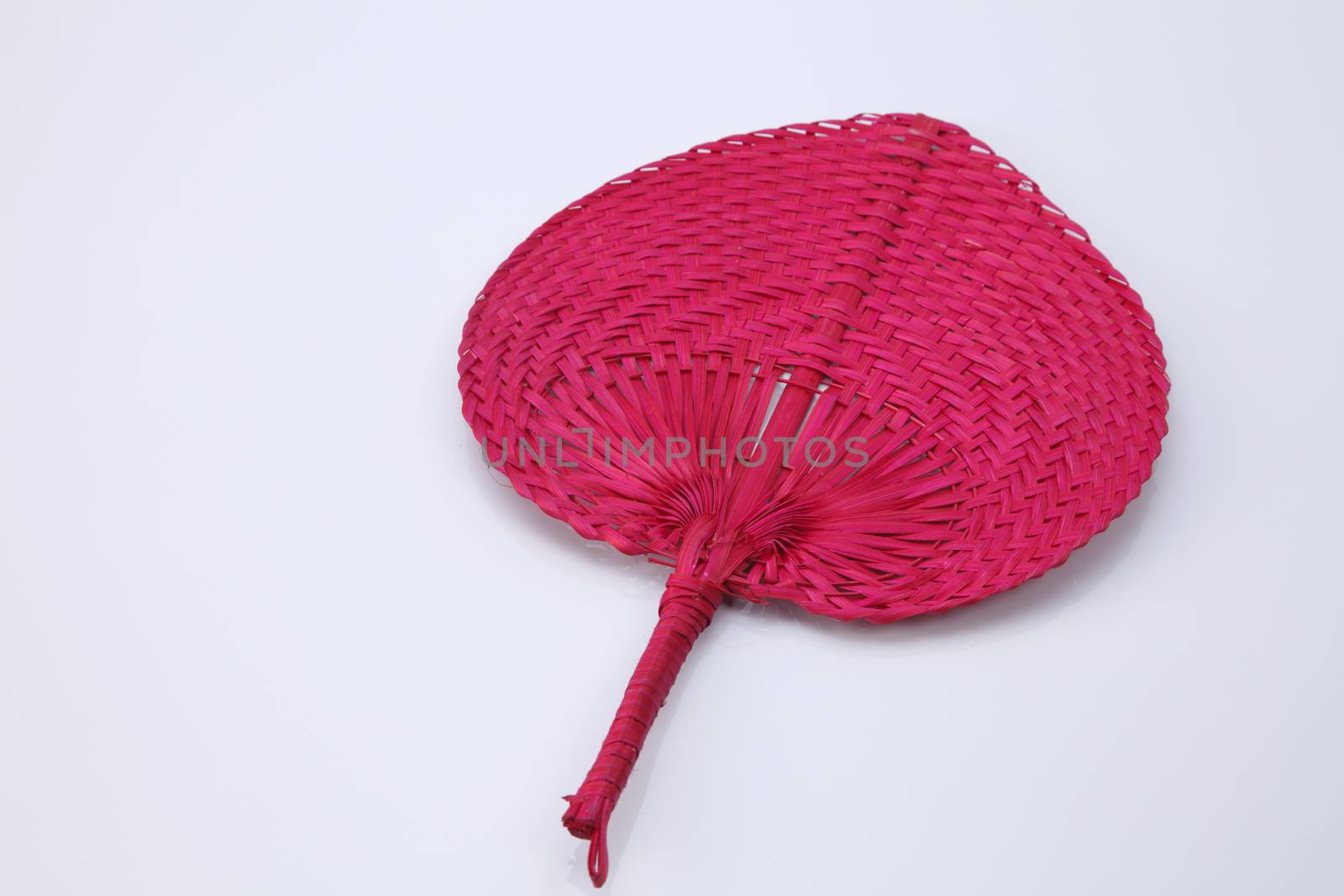 Red color native fan made from palm leaves on white background