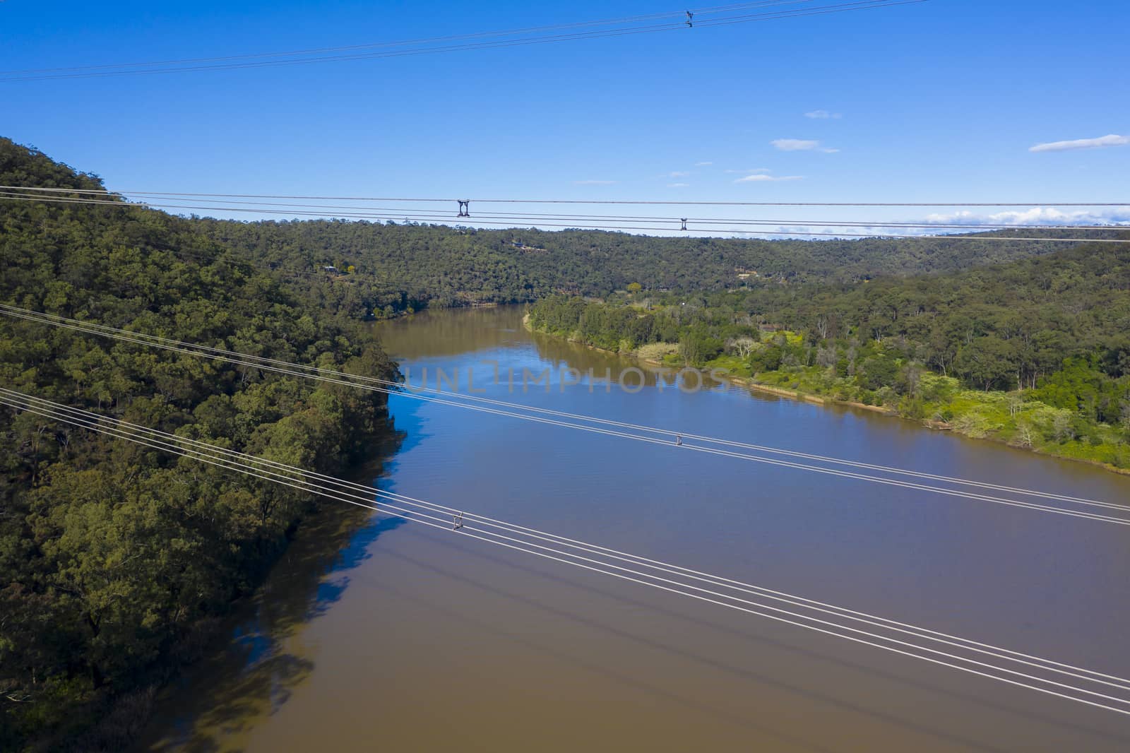 An electricity transmission tower and cables across a river by WittkePhotos