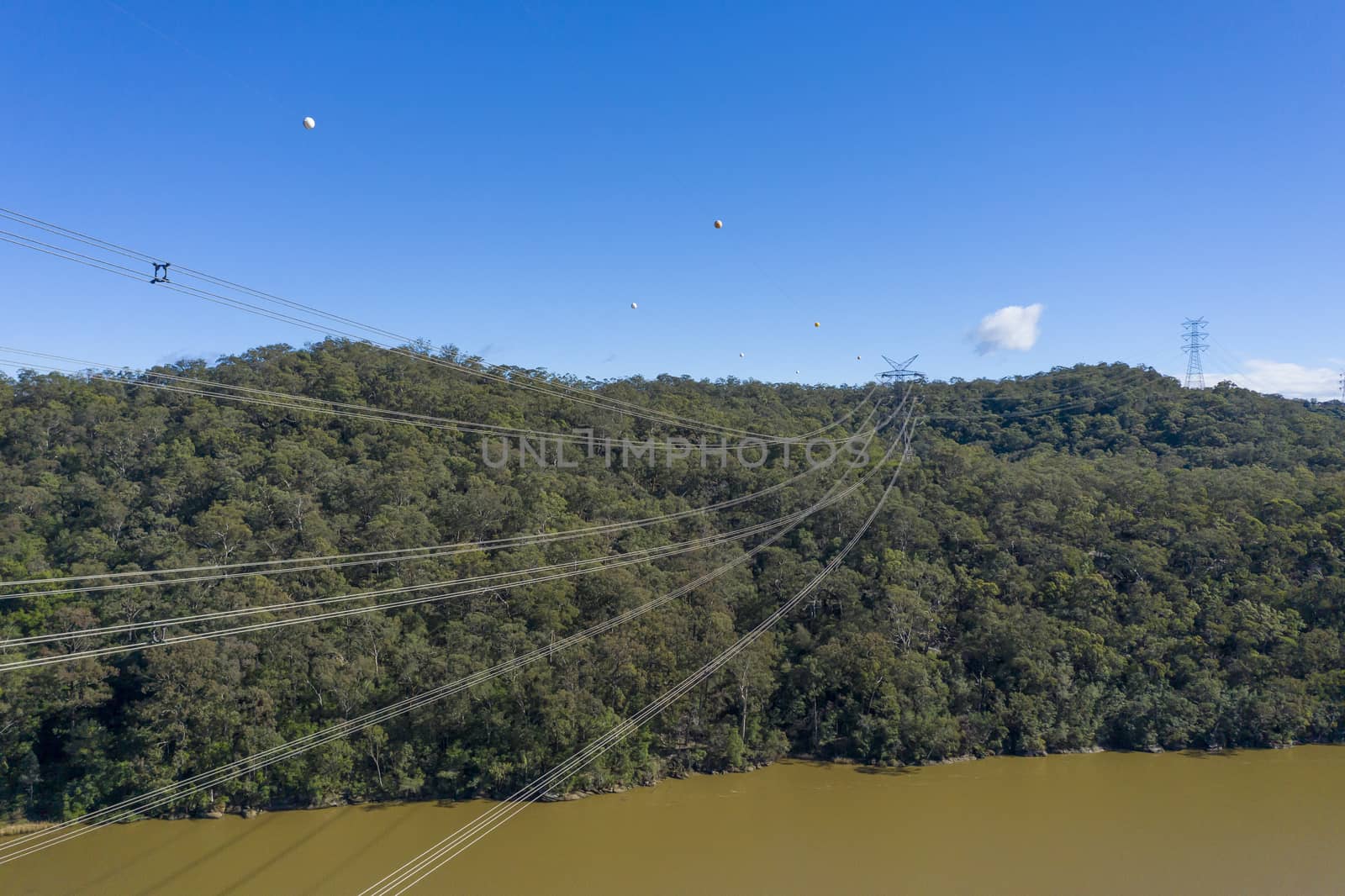 An electricity transmission tower and cables across a river in regional New South Wales in Australia