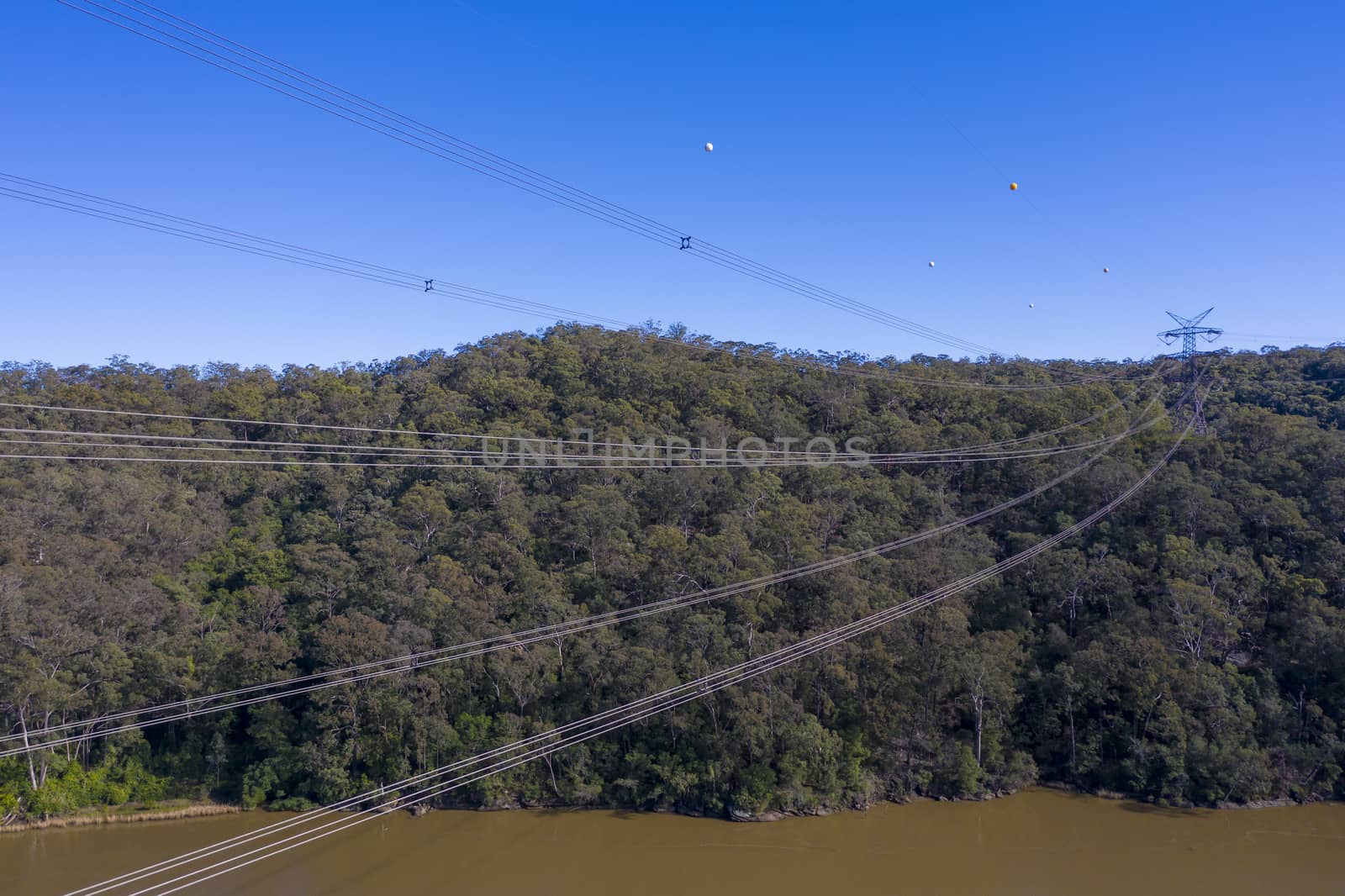 An electricity transmission tower and cables across a river in regional New South Wales in Australia