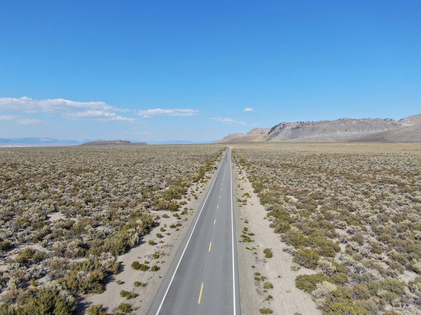 Aerial view of asphalt road in the middle of dusty dry desert land in Lee Vining, Mono County, California, USA