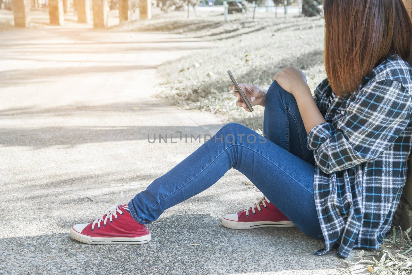 lonely girl sitting in park using her phone