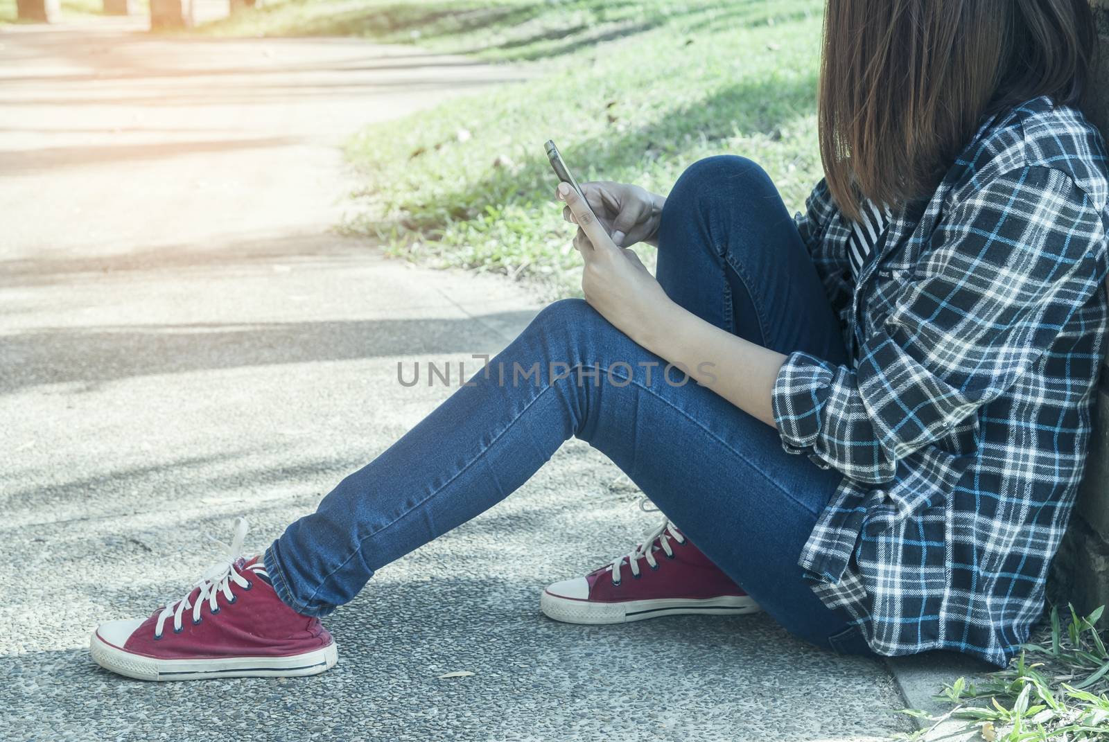 a young woman sitting in park using her phone