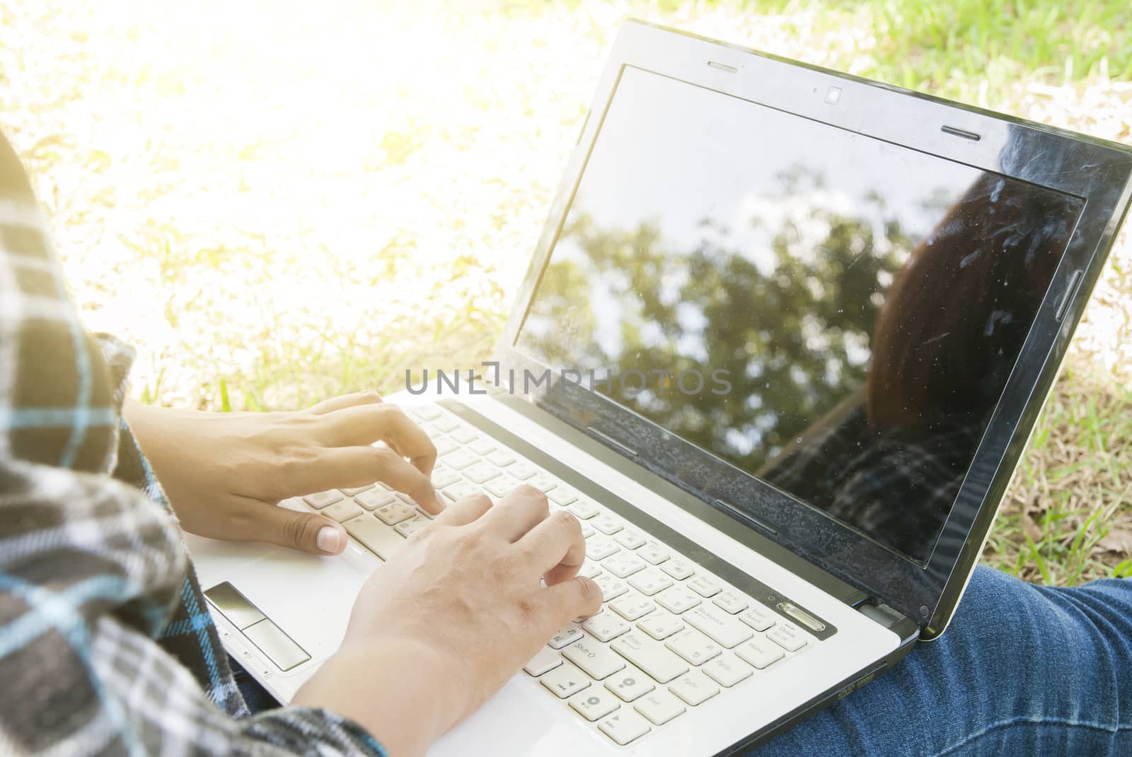 woman using a laptop computer at park with sunlight