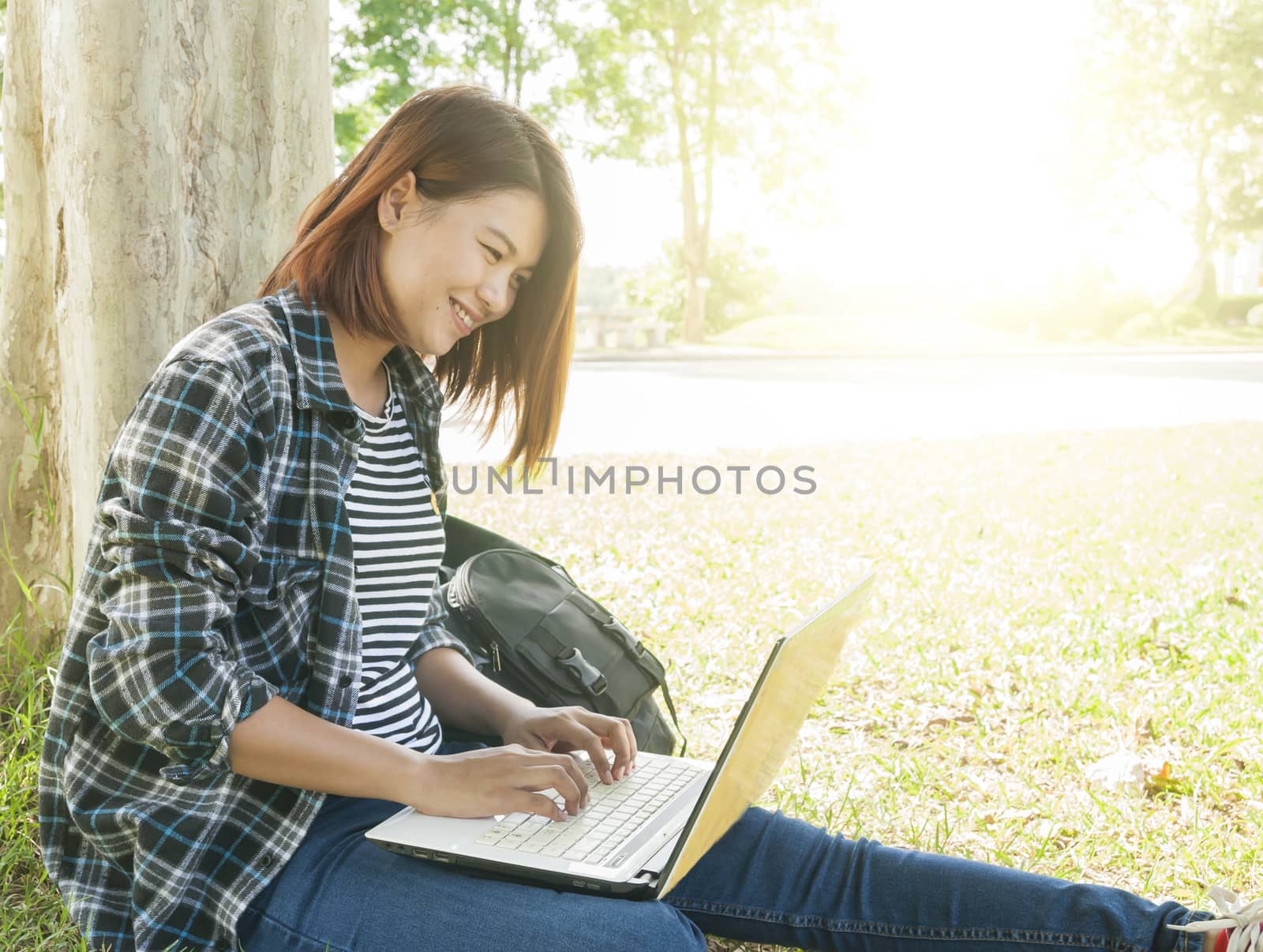 smiling woman sitting using laptop at park