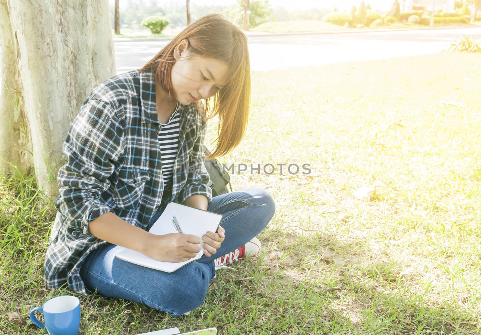 young woman sitting writting notebook at park,bright colors