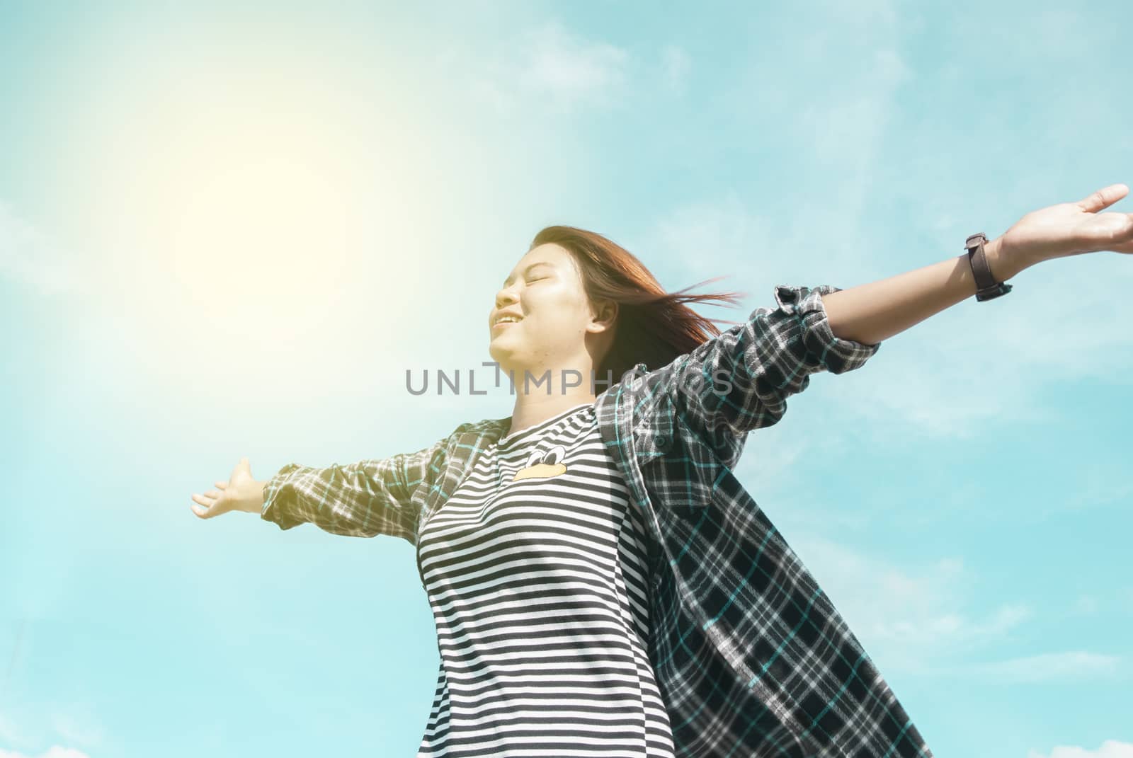 happy young woman dreams to fly with blue sky background