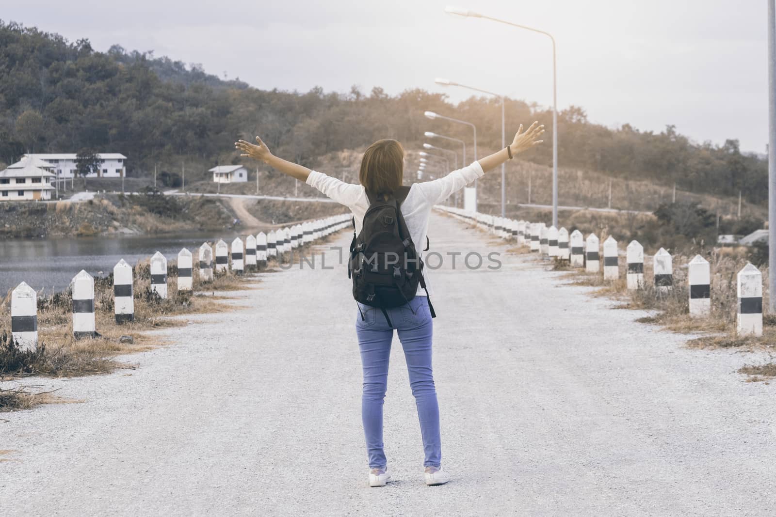 Woman with hands up wearing  backpack on the road,vintage tone