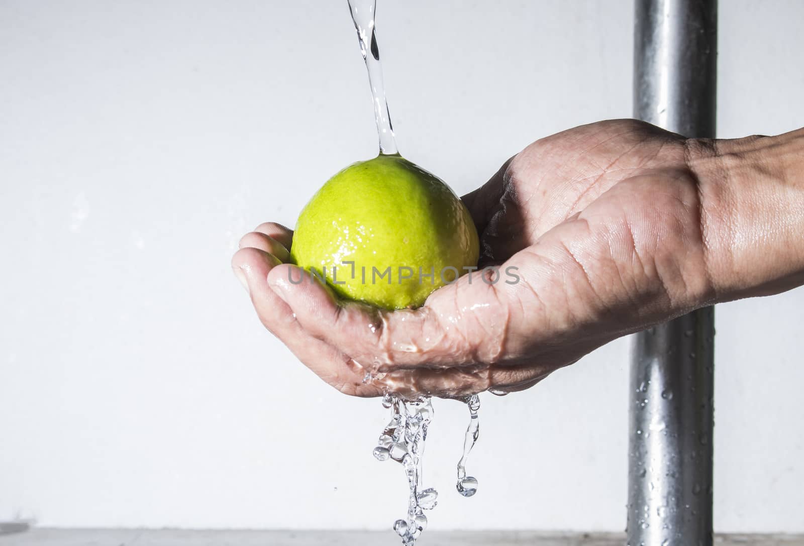 Fresh lemon on male hand cleaning with falling water