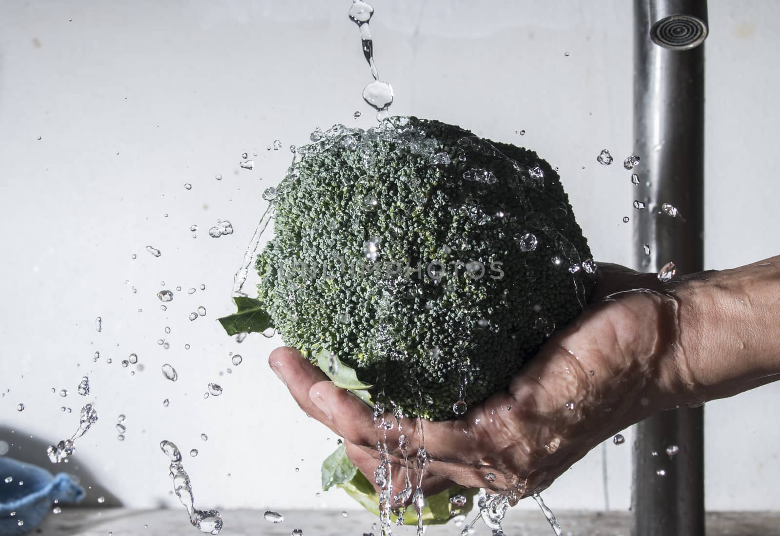 Broccoli on male hand cleaning with water splash by Gobba17