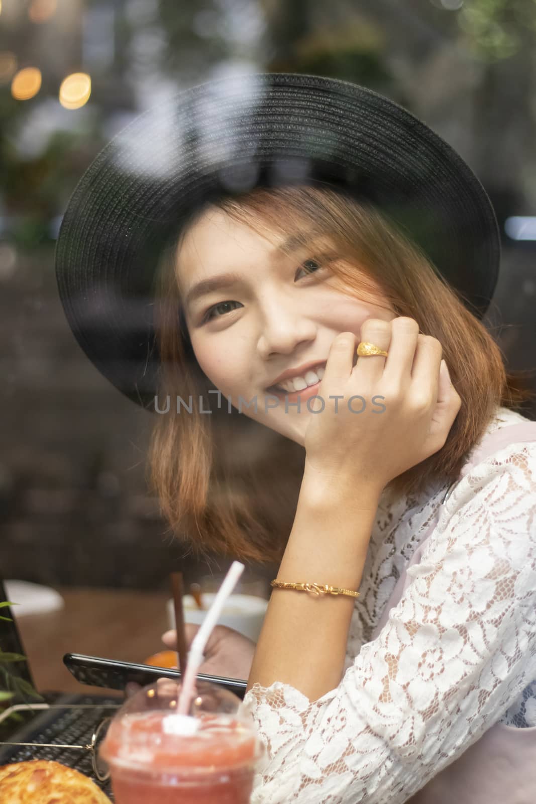 A shot of a beautiful asian woman  in a cafe (shot through window)