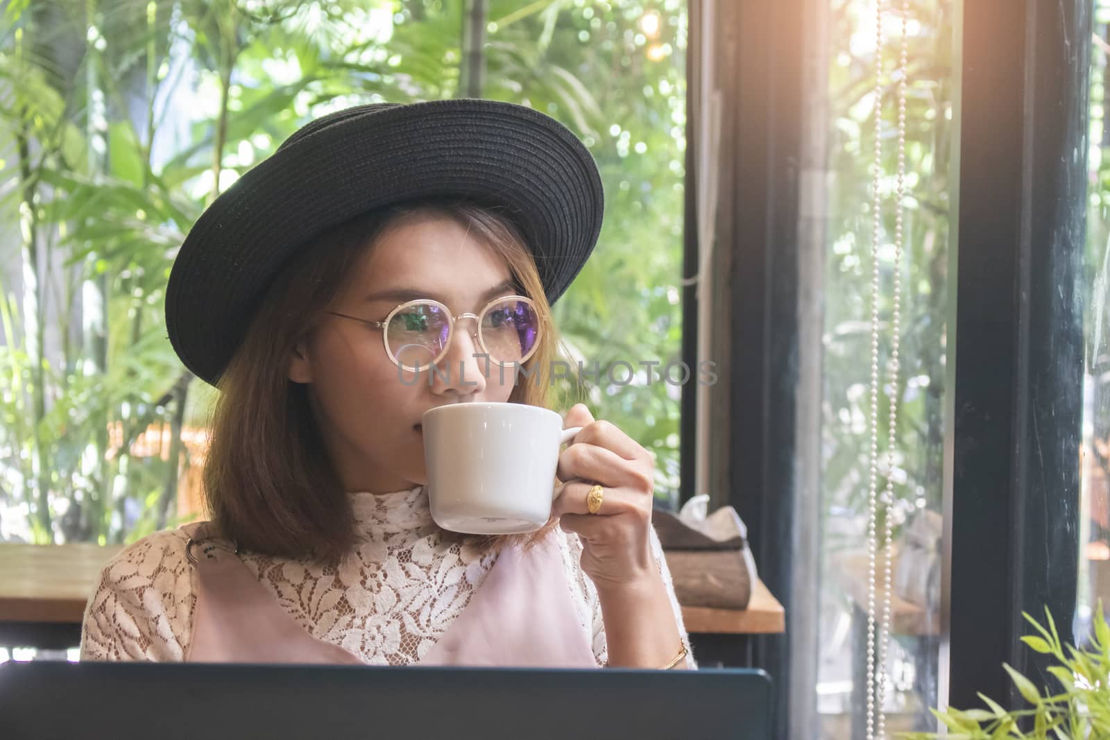 Beautiful Asian woman with hat drinking coffee in cafe
