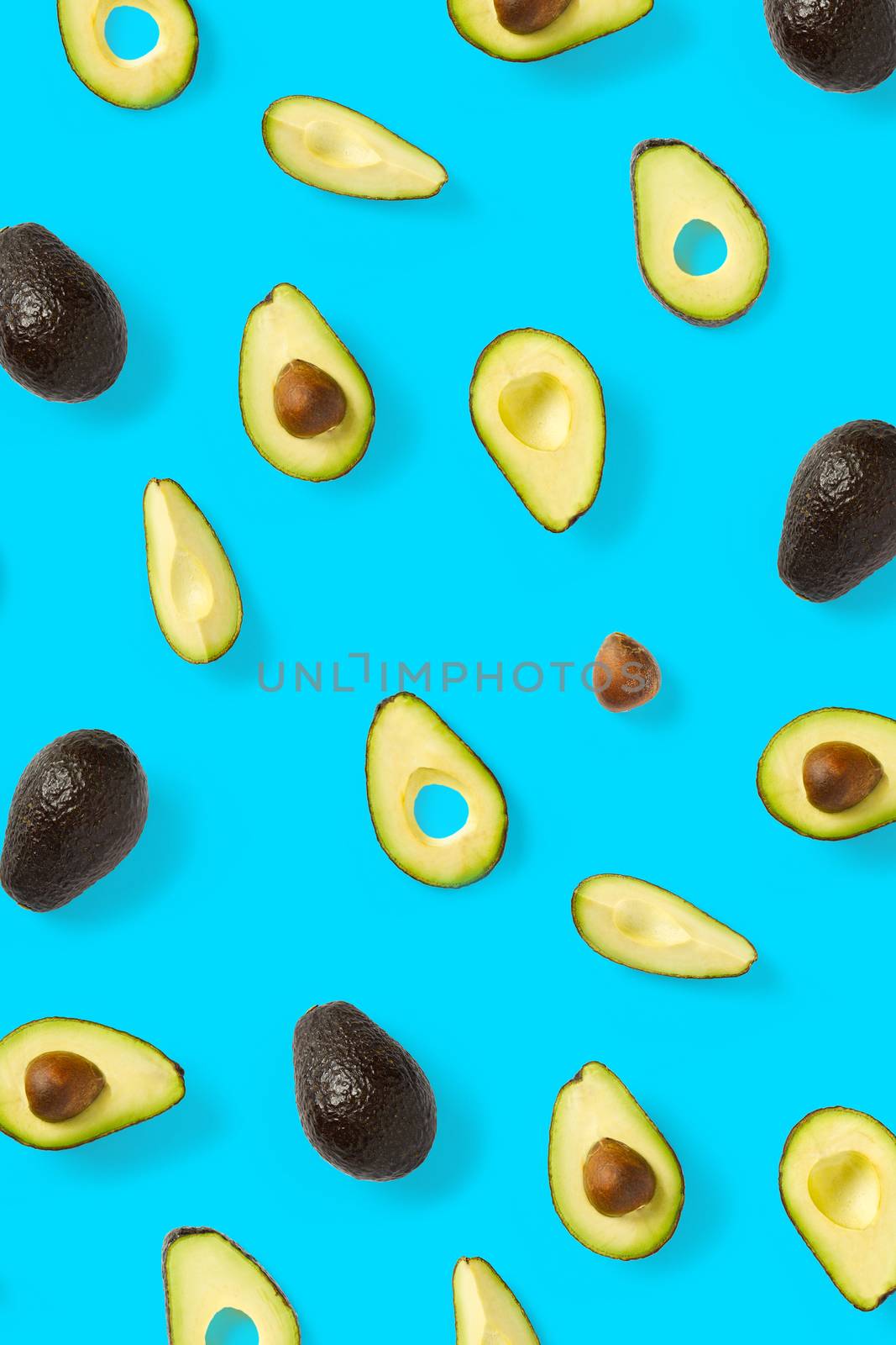 Avocado. Background made from isolated Avocado pieces on blue background. Flat lay of fresh ripe avocados and avacado pieces