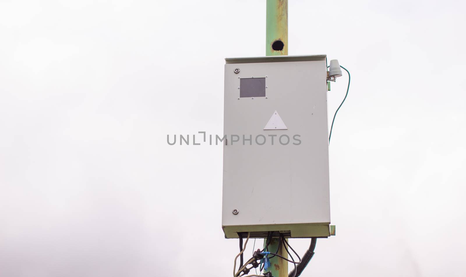 White electric box on a pole outside the house. Industrial, urban electric box