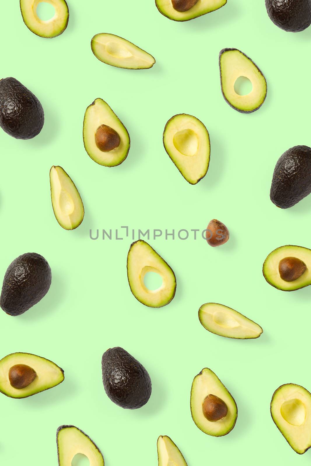 Avocado. Background made from isolated Avocado pieces on green background. Flat lay of fresh ripe avocados and avacado pieces
