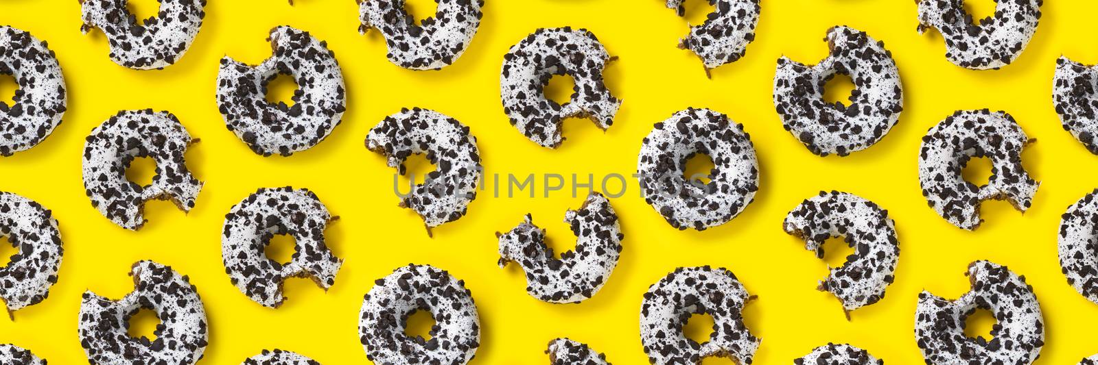donuts on a yellow background top view. Flat lay of delicious nibbled chocolate donuts. used as donut banner or poster background, not pattern. by PhotoTime
