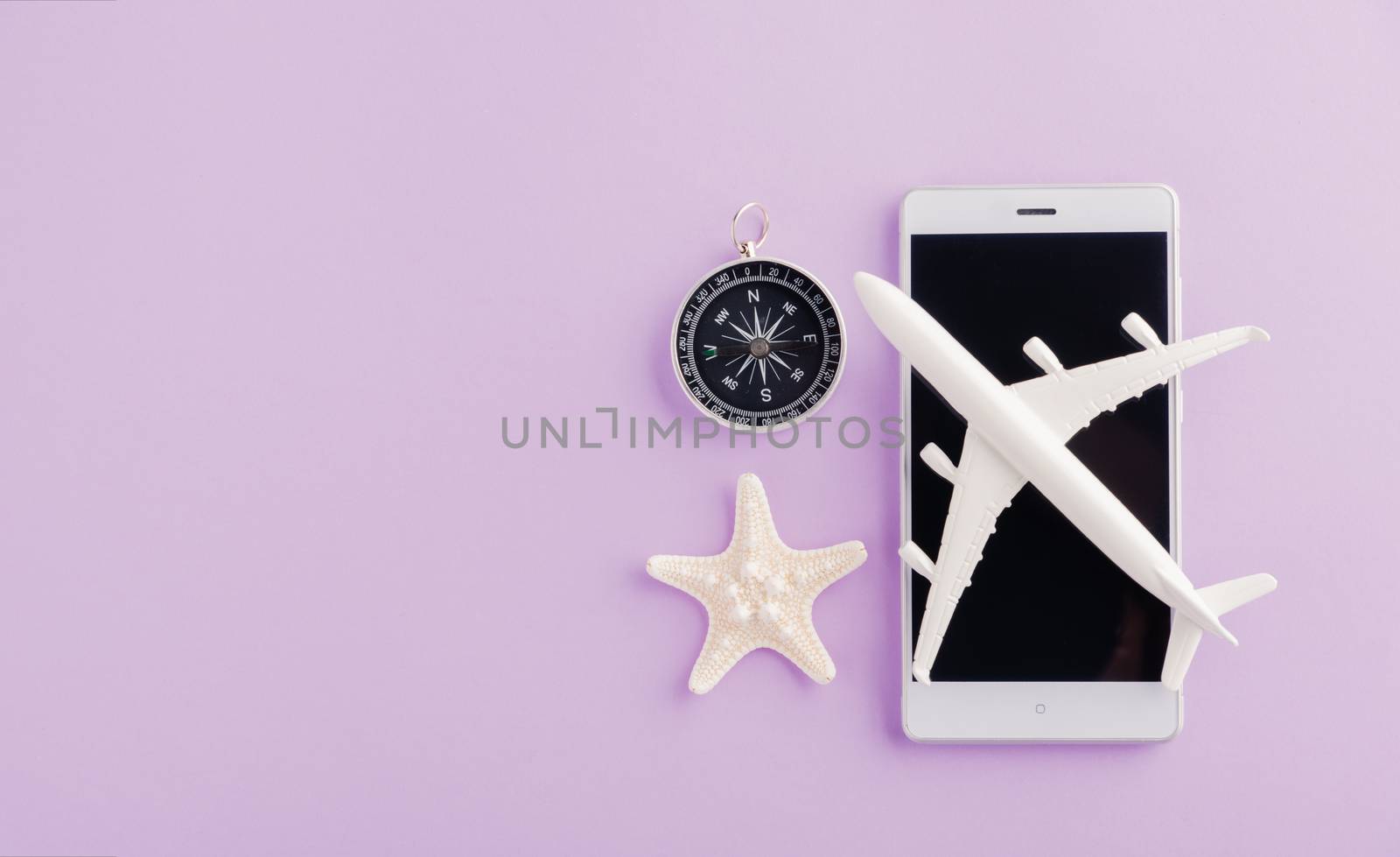 World Tourism Day, Top view of minimal model plane, airplane, starfish, alarm clock, compass on smartphone blank screen, studio shot isolated on a purple background, accessory flight holiday concept