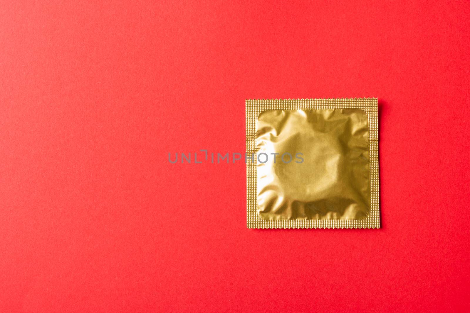 World sexual health or Aids day, Top view flat lay condom in wrapper pack, studio shot isolated on a red background, Safe sex and reproductive health concept