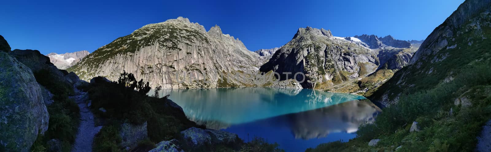 Gelmersee. Dam in the Swiss alps for Hydro power. Clear Blue lake with clear sky.