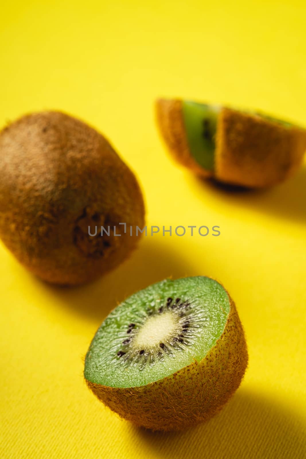 Kiwi fruits half sliced on yellow background, angle view
