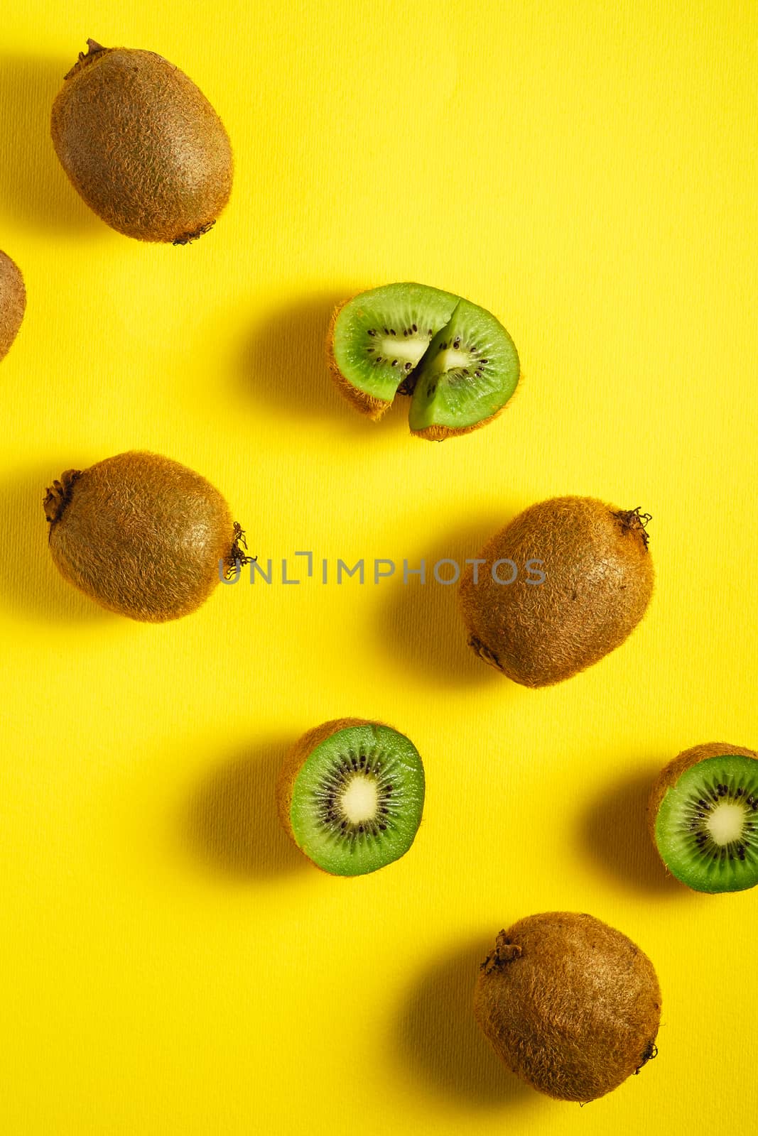 Kiwi fruits half sliced on yellow background, top view flat lay