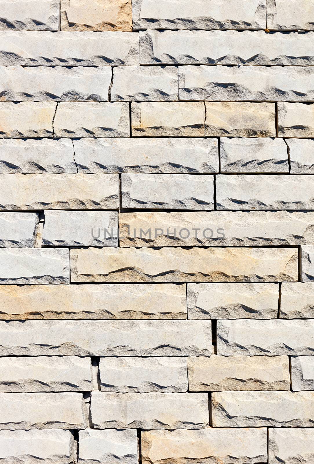 Background and surface texture of tiles of gray and yellow sandstone with chipping and cracks along the perimeter, close-up, vertical image.